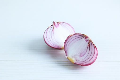 Peeled and Halved Red Onion on a White Wood Table: Two Pieces of Peeled Purple Onion Isolated on White