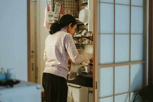 People doing activities in small kitchen of japanese apartment People do cooking activities in the small kitchen of a Japanese apartment in the morning during winter japan small apartment stock pictures, royalty-free photos & images