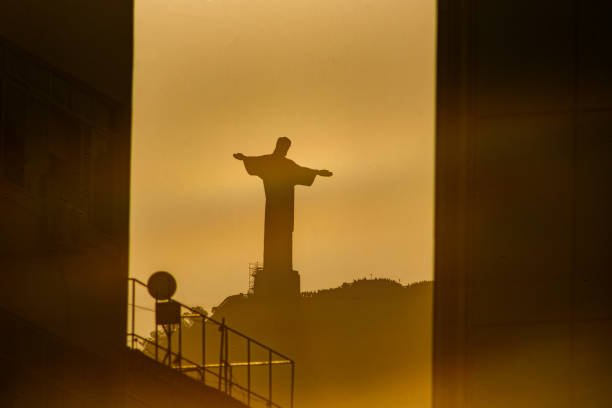 sun setting with Christ the Redeemer in Rio de Janeiro, Brazil - July 6, 2023: Sunset with the statue of Christ the Redeemer seen from the Copacabana neighborhood in Rio de Janeiro.