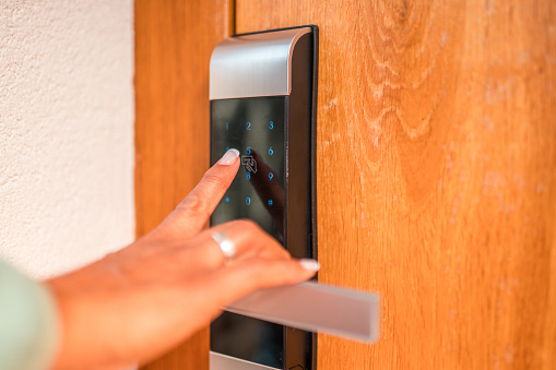 A close-up view of a mature Hispanic female's hand as she enters a code on a digital security keypad, ensuring the safety of her villa while on vacation or at home.