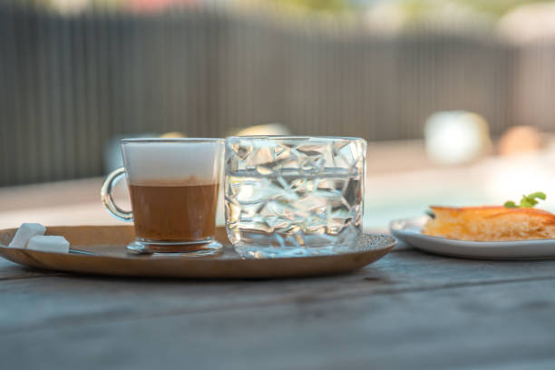 淹れたてのラテと冷水を屋外のウッドテーブルに - latté coffee tray froth ストックフォトと画像