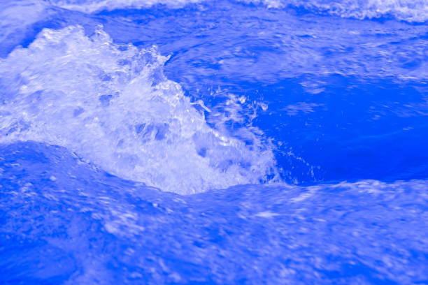 Water surface. Bluewater waves on the surface ripples blurred. Defocus blurred transparent blue colored clear calm water surface texture with splash and bubbles. Water waves with shining pattern.