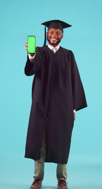 University, graduation and green screen on a phone with a student black man in studio on a blue background. Portrait, education and chromakey on a mobile display with a male college graduate