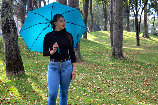 beautiful young woman in a public park with an umbrella in the forest