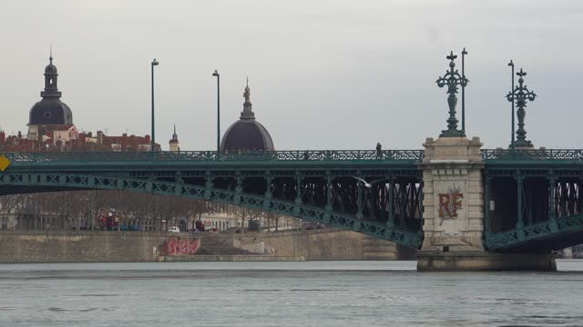 Buses and Pedestrians Cross Lyon's Old Iron University Bridge, Adorned with Arches and Decorative Wrought Iron Stanchions