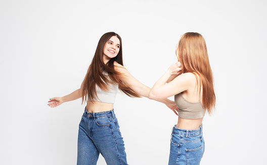 two young women friends with long hair isolated over white grey background