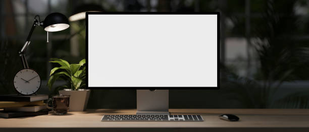 istock A modern home office desk at night with a white-screen computer mockup, dim light from a table lamp. 1986508881