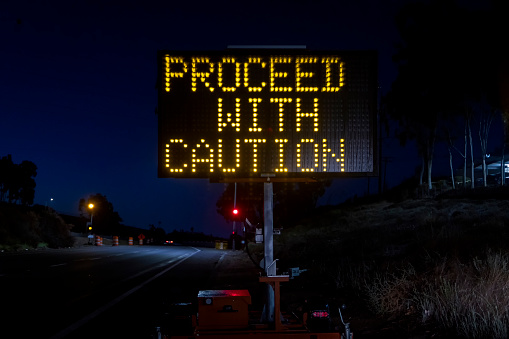 Digital sign at a freeway onramp stating Proceed With Caution