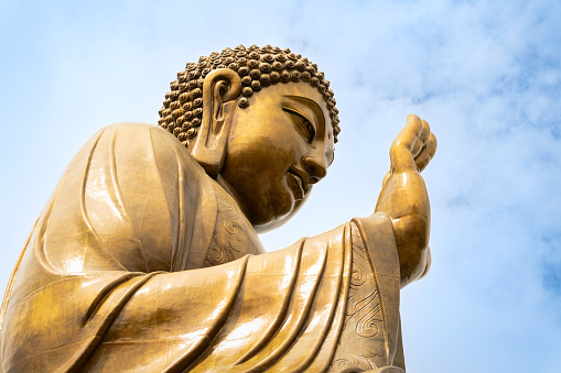 Tall statue of Buddha with raised hands reaching skyward