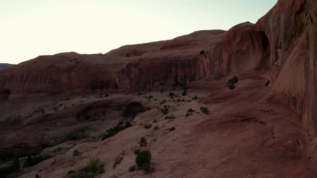 Drone shot flying through the Corona Arch in Moab, Utah at sunset