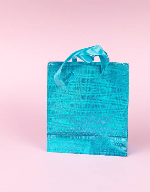 istock A blue shiny gift bag on a pink background. 1986577420