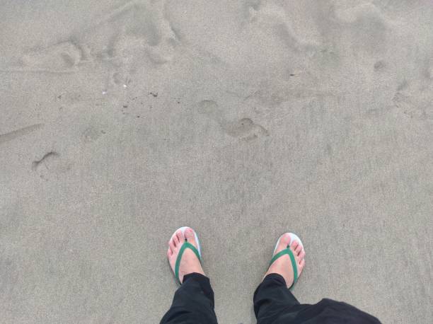 pedestrians walking on the beach in sandals