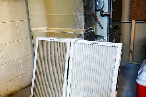 Residential home integrated gas heating furnace and air conditioner cooling unit disposable air circulation filters. The dirty, old, used air circulation filter is on the left. It is quite noticeably much filthier than the brand new clean and fresh filter on the right.