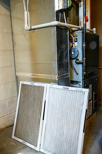 Two disposable air circulation filters for a residential home integrated gas heating furnace and air conditioner cooling unit. The old, dirty used air duct filter on the left is quite obviously much filthier than the brand new fresh, clean filter on the right.