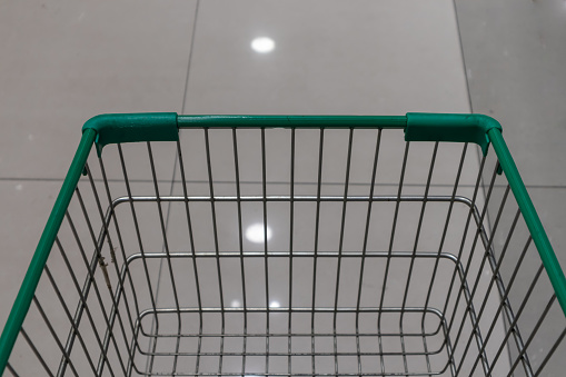 Empty green shopping cart in supermarket aisle
