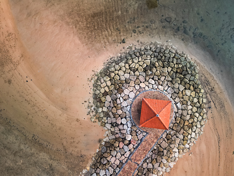 Wave breaker structure made from rocks with gazebo for tourist at Sanur Beach, Bali, Indonesia. Breakwater constructed at coastal area