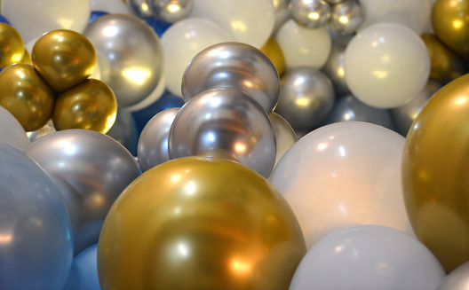 Horizontal shot of bunch of silver golden white and blue colored shiny party balloons for happy cheerful celebrations backdrops, background, wallpaper