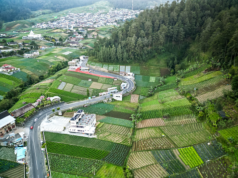 Aerial view of Mount Lawu mountainside in the morning with vegetable garden and village settlements or housing in Bukit Sekipan, Tawangmangu, Central Java, Indonesia.