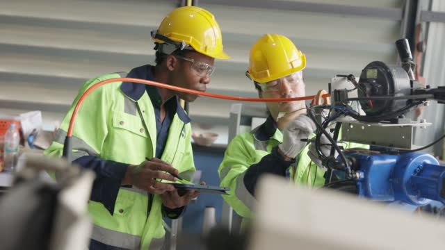 Two engineer using multimeter measure robot arm  and record data