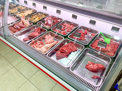 Display case and refrigerator in a Indonesian butcher shop stocking various packaged cuts of meat, offal, minced and sliced. Natural whole healthy food, animal protein, essential amino acid concept.