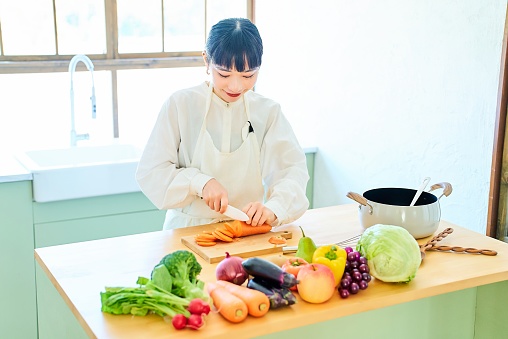 Young woman cutting ingredients with a knife at kitchen