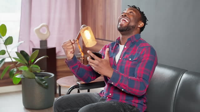 black man rejoicing by win in mobile game or goal of favorite team, portrait of smartphone user
