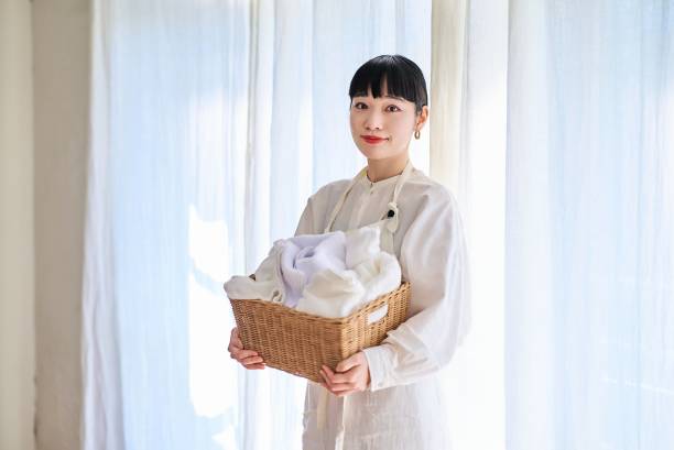 istock Young woman standing with laundry 1986849532