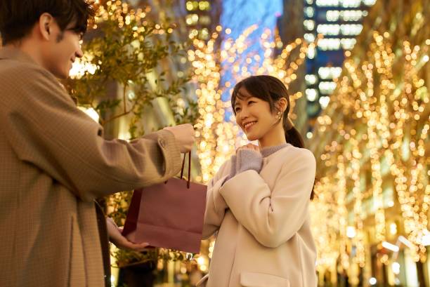 mann und frau mit geschenken und ein beleuchtetes stadtbild - weißer tag japanischer feiertag stock-fotos und bilder