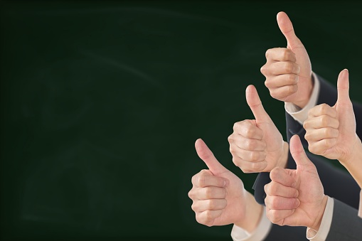 Business person giving good sign on blackboard background