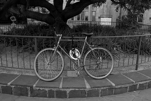 Melbourne, Australia – March 23, 2022: A bicycle resting against a railing in a park in grayscale