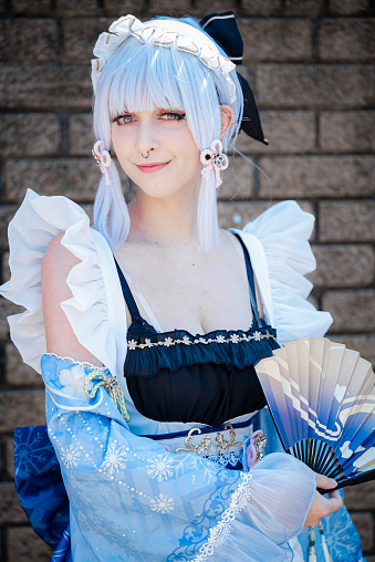 A female cosplayer in a vintage blue dress with blue hair