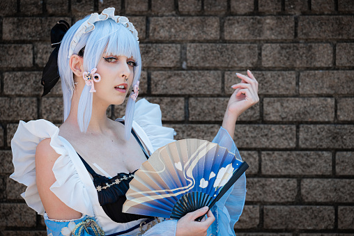 A female cosplayer in a vintage blue dress with blue hair