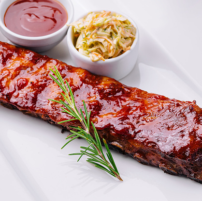 Grilled pork ribs in barbecue sauce and honey with sauerkraut on white plate