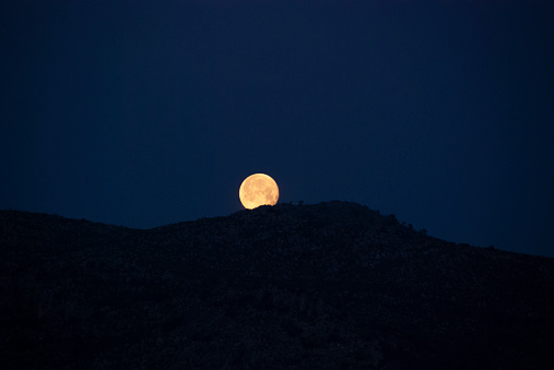 Full moon rising over the hill