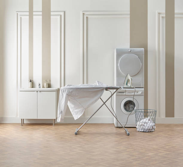 istock Washing dryer machine and ironing table interior style, laundry room, white and brown vertical wall background. 1987032601