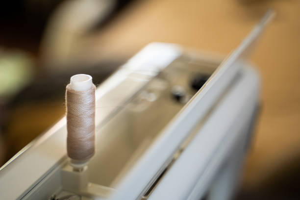 Close-up of hands guiding purple yarn through a mechanical knitting machine, working on a textile project