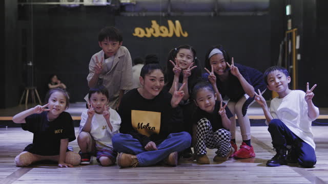 Happy Japanese hip hop teacher with her young students