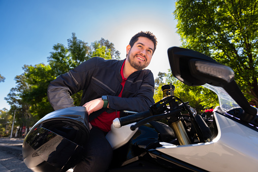 Man with a helmet in a leather jacket riding a scooter isolated on white background