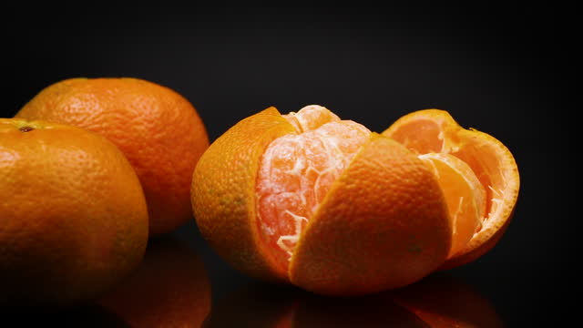 ripe tangerines with peel on black background