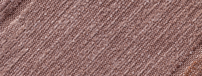 Dark brown color background of knitted textile material with diagonal pattern. Fabric backdrop with umber striped texture closeup.