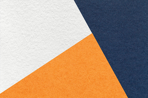 Texture of craft navy blue, white and orange shade color paper background, macro. Structure of vintage abstract cardboard with geometric shape and gradient. Felt backdrop closeup.