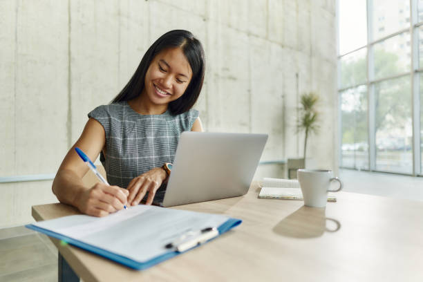istock Happy Asian businesswoman writing her plans while working in the office. 1987106606