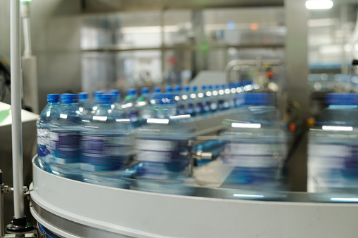 Part of moving production line with capped plastic bottles containing mineral water or some other drink in large modern factory