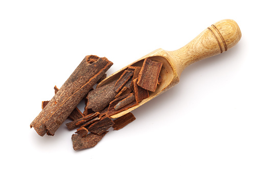 Top view of Organic Cinnamon sticks (Cinnamomum verum), in a wooden scoop. Isolated on a white background.