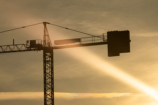 A sun ray illuminate a crane installed on a building site