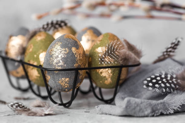 istock Stylish beautiful Easter eggs with golden enamel, willow branches and feathers on a gray background. The concept of happy Easter 2024. 1987130019