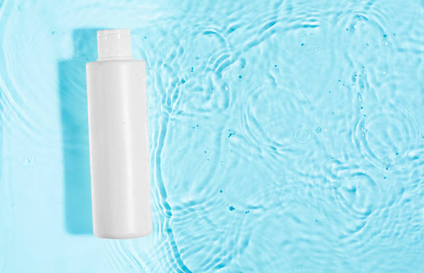 istock Cosmetic moisturizer with hyaluronic acid, micellar emulsion on blue water background with splashes. Mockup of cosmetic packaging 1987146108
