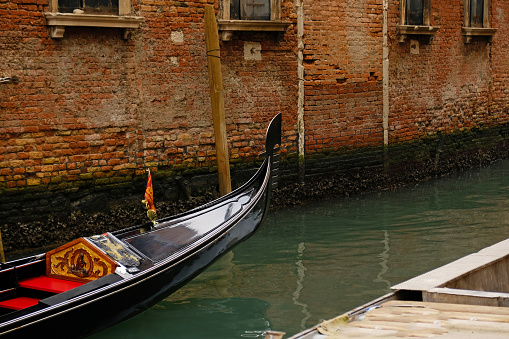 Venice, Italy - October 12th 2022:  Gondola crossing the Canal Grande with a view to a row of everyday motorboats