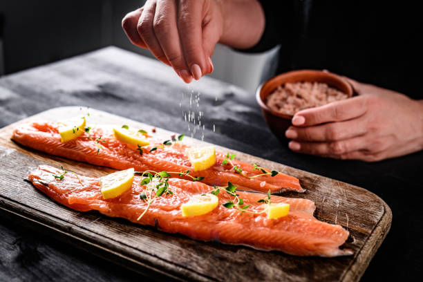 Girl Adding A Pinch Of Salt To Raw Red Trout Fish