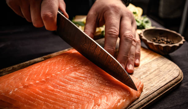 istock Sushi chef cuts raw salmon with knife 1987166115